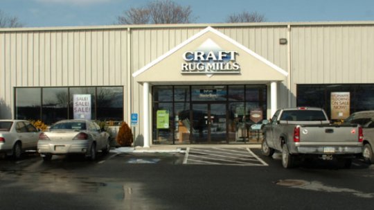 The exterior of the Craft Rug Mills building in Easton, PA, showing the main entrance and parking lot.