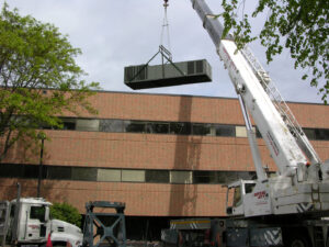 A crane lifting a large commercial HVAC unit onto a building for installation by AireCom HVAC in Columbus, OH.