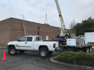 A crane lifting a commercial HVAC unit onto a rooftop for Gagles Heating in Salem, OR.