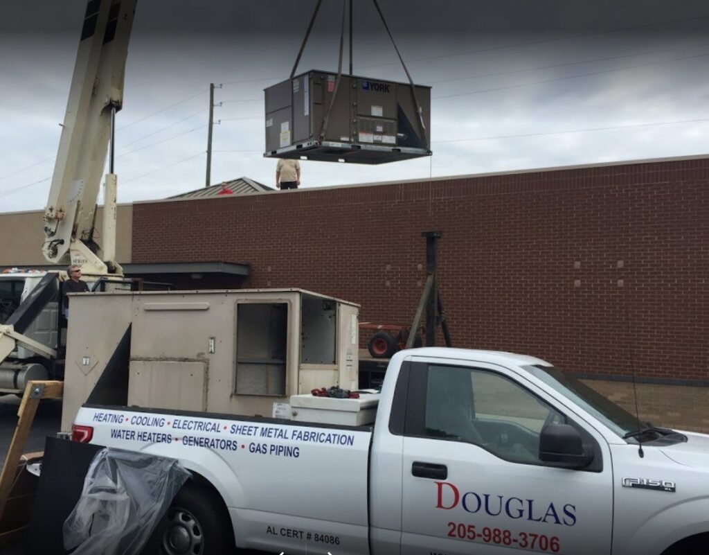 A crane lifting a large commercial York HVAC unit onto a rooftop, indicating installation by Douglas Cooling & Heating in Pelham, AL.