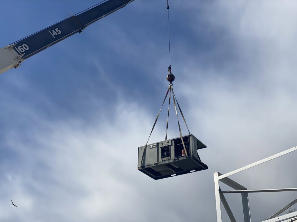 A crane lifting a large commercial HVAC unit during installation by Vanessa Service HVAC in Falls Church, VA.