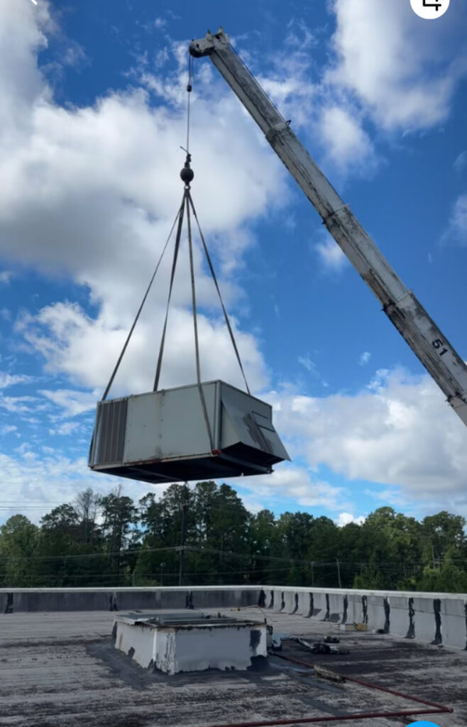 A crane lifting a large commercial rooftop HVAC unit during installation or replacement by Moreau's Heating & AC in Lake Charles, LA.