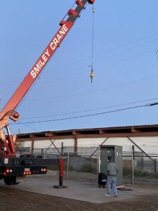 A crane lifting an electrical cabinet during installation, a service provided by EV Electric LLC in Mesa, AZ