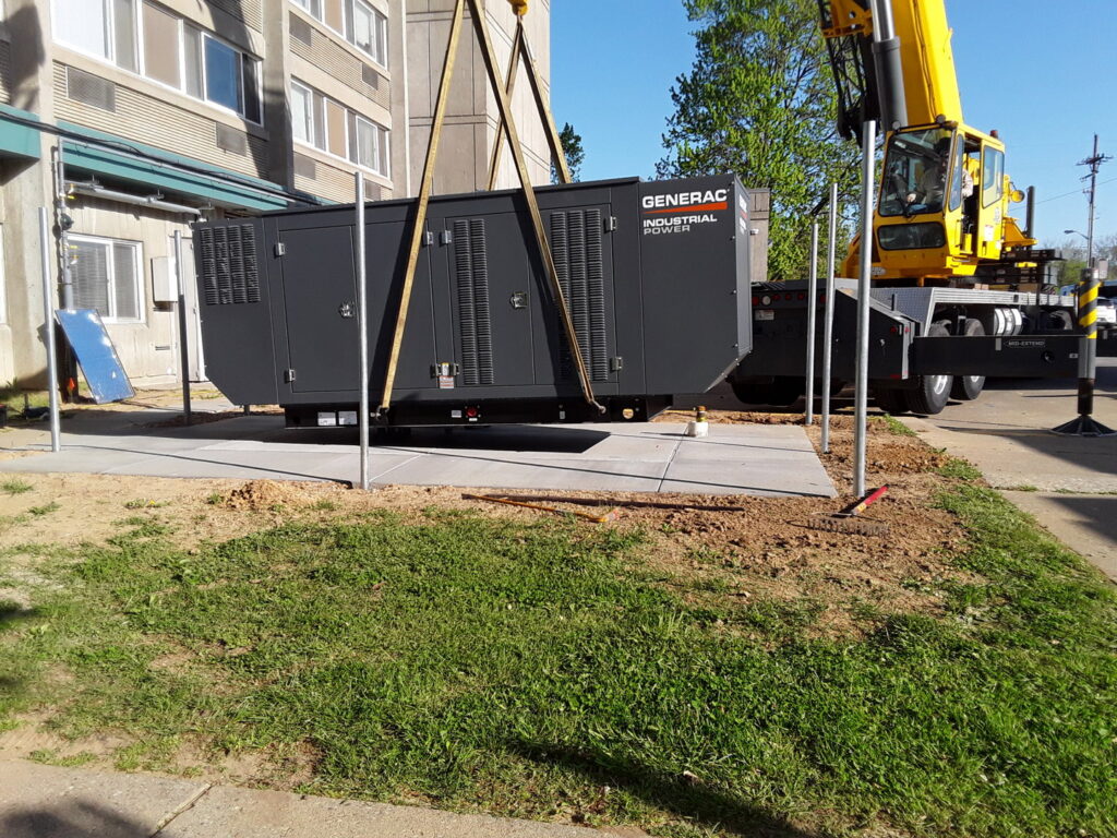 A crane lifting a large Generac industrial power generator into place for installation by Varitech, Inc. in Louisville, KY.