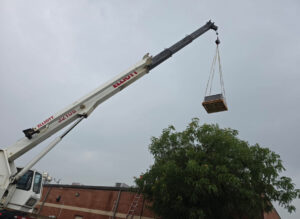 A crane lifting an HVAC component during an installation by Tornado Heating and Air in Tulsa, OK.