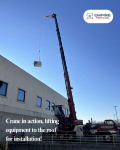 A crane lifting HVAC equipment to a rooftop for installation by Empire Tech, Inc. in Schaumburg, IL.