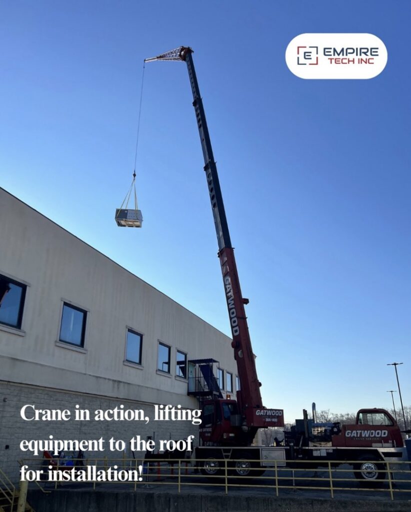 A crane lifting HVAC equipment to a rooftop for installation by Empire Tech, Inc. in Schaumburg, IL.