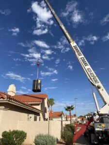 A crane lifting an HVAC unit over a house for installation by Mountainside Air in Phoenix, AZ.
