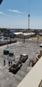 A crane lifting an HVAC unit from the ground for installation by Klimate Concepts in Lubbock, TX.