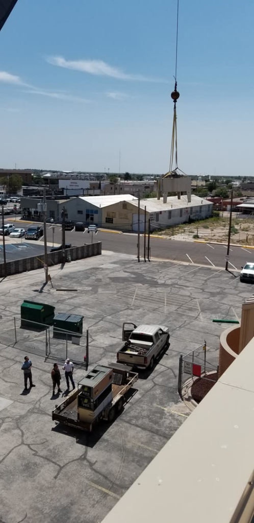 A crane lifting an HVAC unit from the ground for installation by Klimate Concepts in Lubbock, TX.