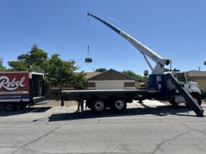 A crane lifting an HVAC unit from a Rebel Refrigeration truck during an installation in Las Vegas, NV.