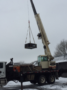 A crane lifting a large HVAC unit from a truck, demonstrating professional equipment handling by Spencer Heating & Air Conditioning in Norcross, GA.