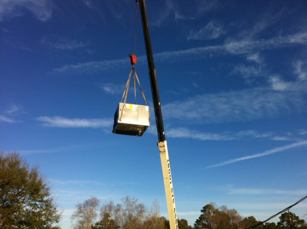 A crane lifting an HVAC unit into place during an installation project by R&B Cooling&Heating in Abbeville, LA.