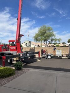 A crane lifting an HVAC unit for installation or removal, with technicians on site from Rusty's Air Conditioning And Heating in Mesa, AZ.