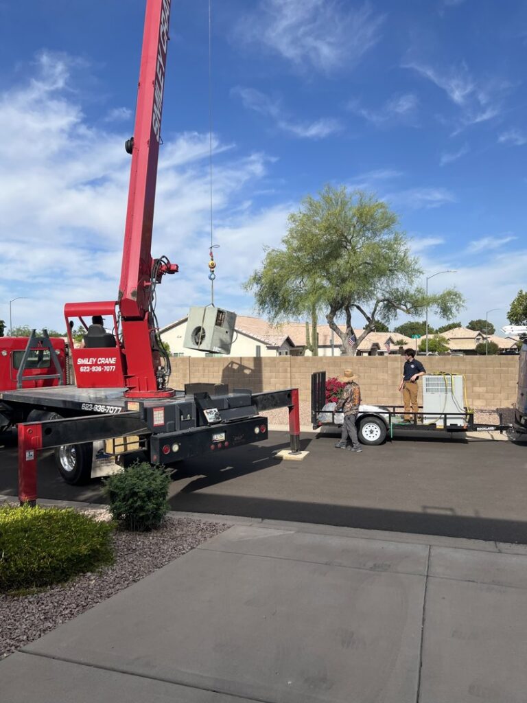 A crane lifting an HVAC unit for installation or removal, with technicians on site from Rusty's Air Conditioning And Heating in Mesa, AZ.