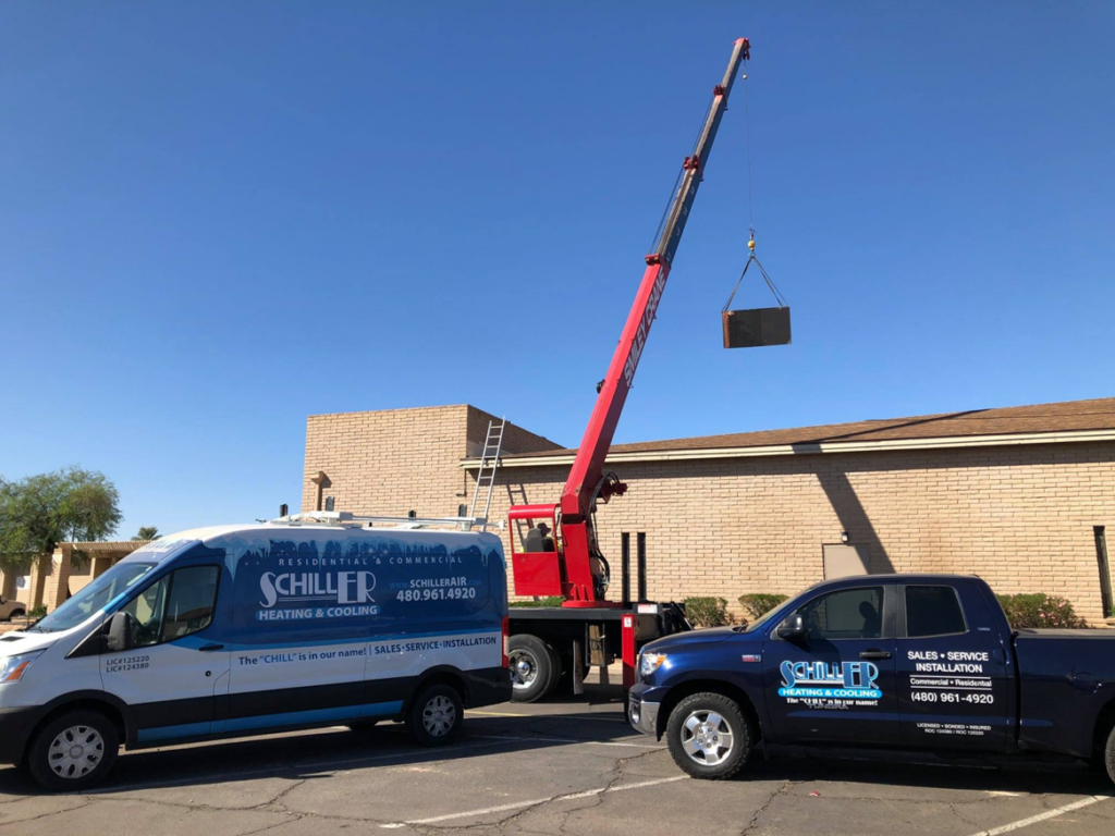A crane lifting an HVAC unit onto a roof during an installation by Schiller Heating & Cooling in Tempe, AZ.