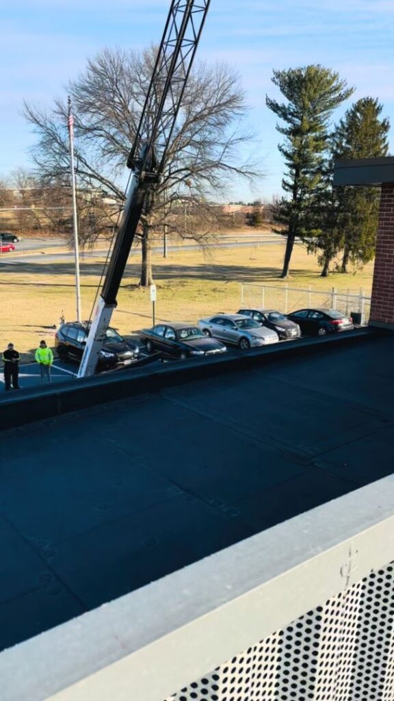 A crane lifting an HVAC unit onto a commercial rooftop for installation by American Air LLC in Moncks Corner, SC