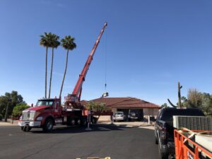 A crane lifting an HVAC unit over a residential home for installation by Hellerud Air in Peoria, AZ.