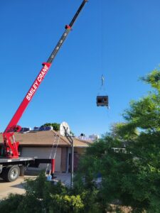 A crane lifting a new HVAC unit onto a rooftop for installation by J & M Cooling & Heating LLC in Peoria, AZ.