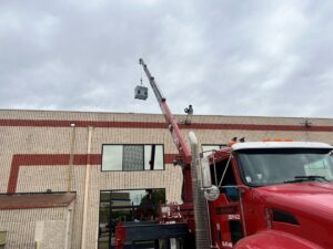 A crane lifting a new HVAC unit onto a commercial building roof for installation by MB Heating and Air in Northridge, CA.