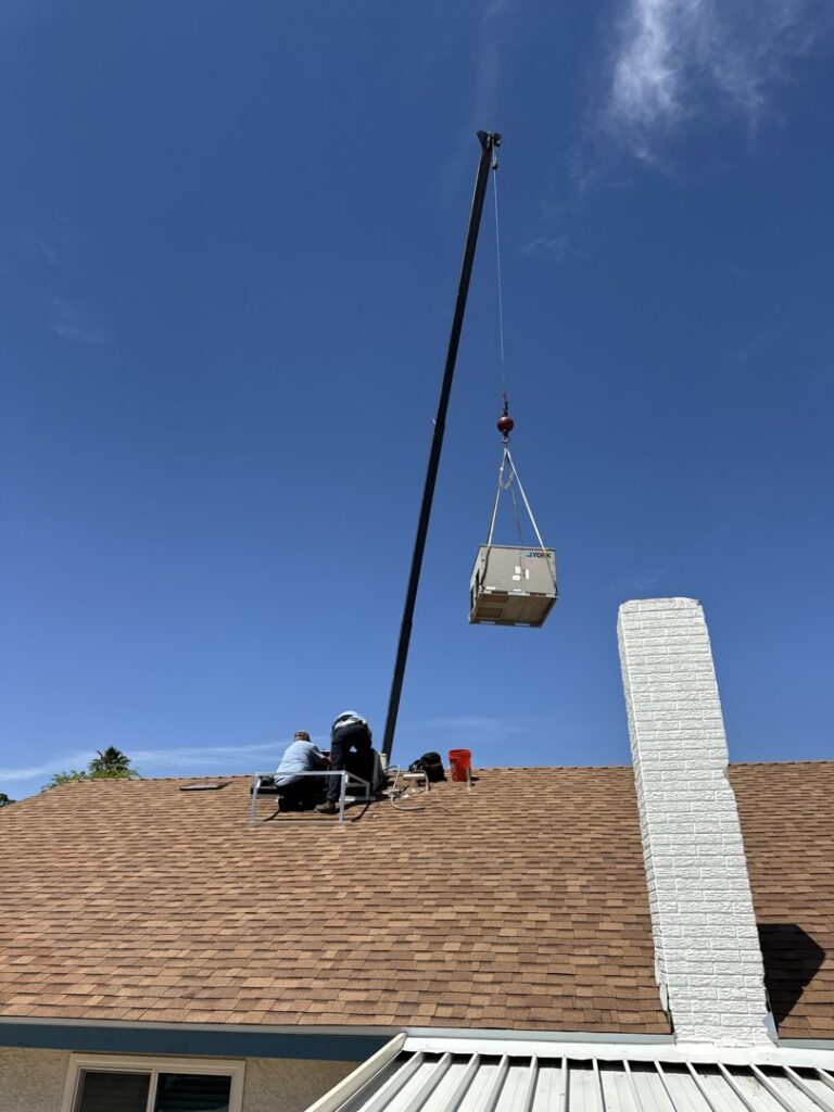 A crane lifting an HVAC unit onto a residential roof for Rebel Refrigeration in Las Vegas, NV.