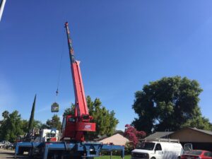 A crane lifting a new HVAC unit onto a rooftop for installation by Tokay Heating, Air & Plumbing in North Highlands, CA.