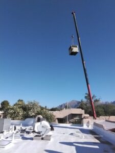A crane lifting a new HVAC unit onto a commercial rooftop for installation by Heating & Air Paramedics - Tucson in Tucson, AZ.