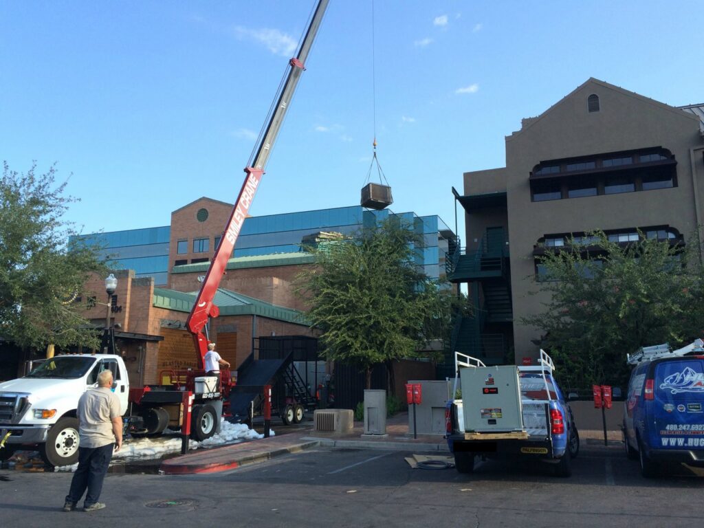 A crane lifting an HVAC unit for rooftop installation by Hughes Air Heating & Cooling in Mesa, AZ.
