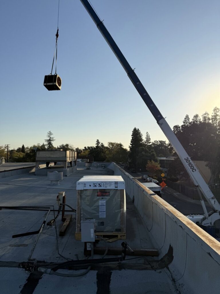 A crane lifting an HVAC unit onto a rooftop for installation by Jaguar Heating & Air in Sacramento, CA