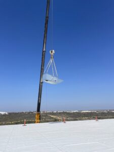 A crane lifting an HVAC unit onto a rooftop for installation by Norway Air Conditioning Inc. in Laredo, TX.