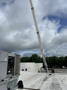 A crane arm extending towards a rooftop, indicating heavy equipment use for HVAC installation by Underwood Heating and Air Conditioning in Phenix City, AL