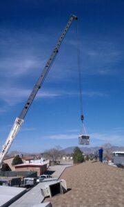 A crane lifting an HVAC unit onto a rooftop for installation by Weather Masters, Inc. in Mesa, AZ.