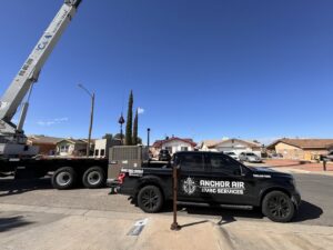 A crane lifting a large HVAC unit for installation, with an Anchor Air service truck nearby in El Paso, TX