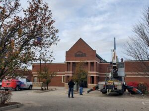 A crane lifting a new commercial HVAC unit onto a building rooftop for Frederick Plumbing, Heating & Air Conditioning in Wichita, KS