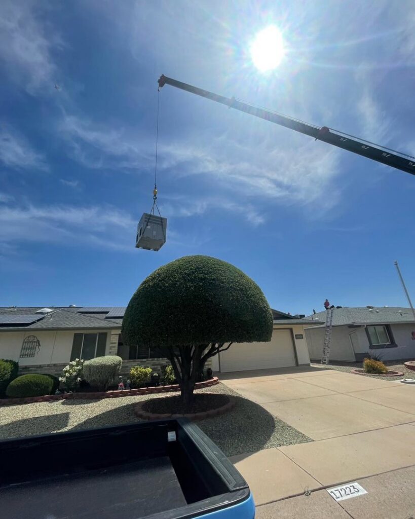 A crane lifting a new HVAC unit onto a residential roof for installation by AZ Perfect Comfort in Phoenix, AZ.