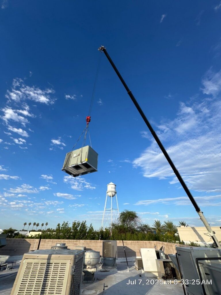 A crane lifting a new HVAC unit onto a commercial rooftop for installation by Kade Mechanical in Phoenix, AZ.