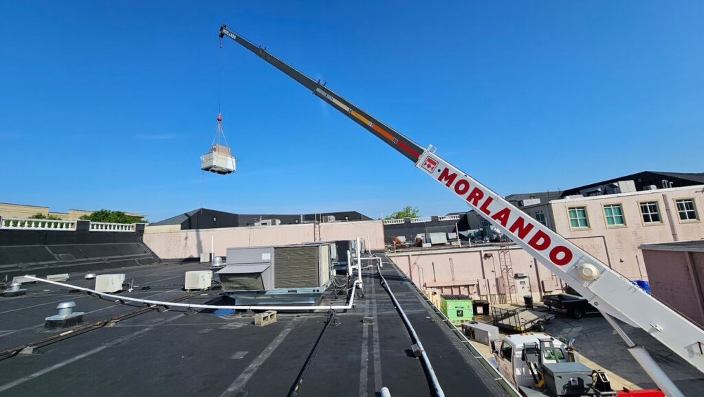 A crane lifting a new HVAC unit onto a commercial rooftop for installation by Peak Seasons HVAC in Raleigh, NC.