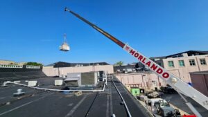 A crane lifting a new HVAC unit onto a commercial rooftop for installation by Peak Seasons HVAC in Raleigh, NC.