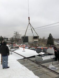A crane lifting a new commercial rooftop HVAC unit during installation by 5280 Cooling Heating & Refrigeration in Lakewood, CO