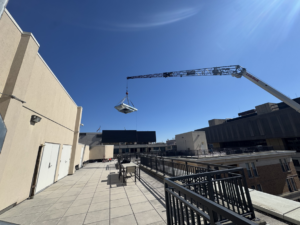 A crane lifting a large rooftop HVAC unit for installation on a commercial building by APEX HVAC Solutions LLC in Frederick, MD.