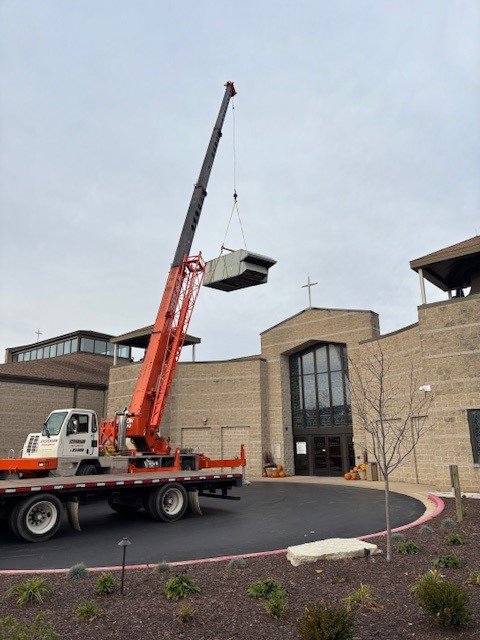 A crane lifting a new rooftop HVAC unit onto a commercial building, installed by R.J. O'Neil Inc. in Montgomery, IL.