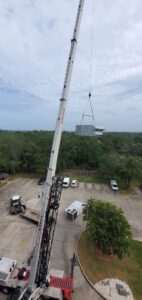 A crane lifting a large rooftop HVAC unit during installation by TEMCO of Gulf Coast Inc. in Biloxi, MS.