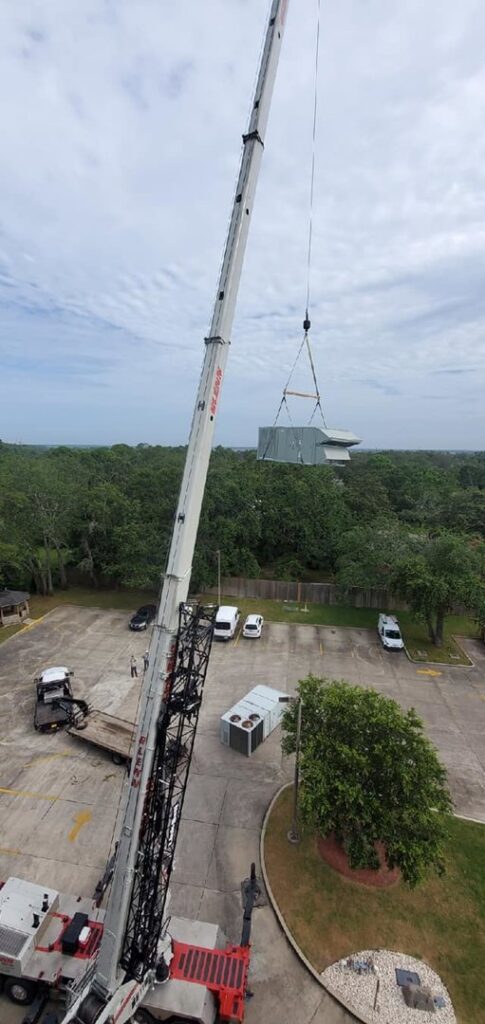 A crane lifting a large rooftop HVAC unit during installation by TEMCO of Gulf Coast Inc. in Biloxi, MS.