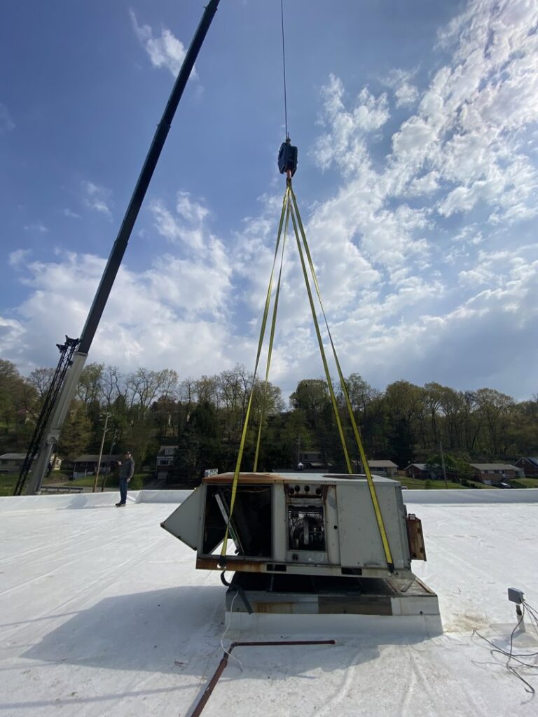 A crane removing an old commercial rooftop HVAC unit from a building, performed by PureAir HVAC in Bel Air, MD.