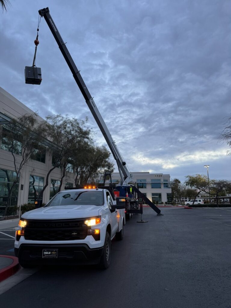 A crane truck lifting an HVAC component at a commercial building for Rogue Mechanical in Las Vegas, NV.