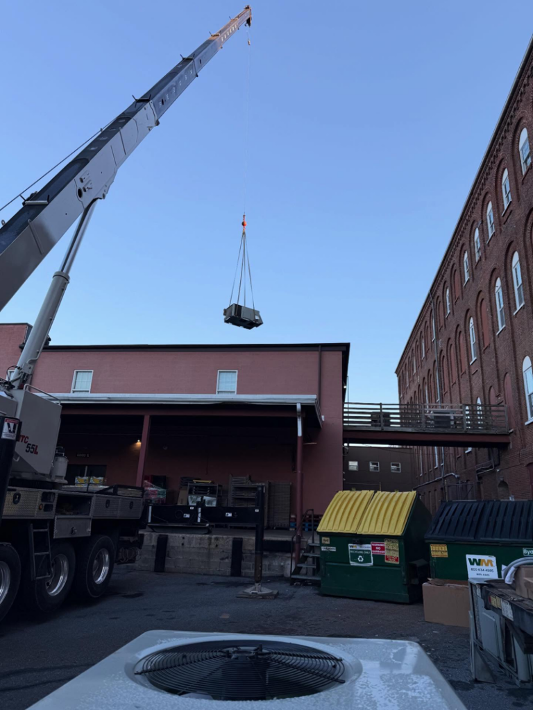 A crane truck lifts a new HVAC unit for installation at a commercial building by JK Mechanical in Willow Street, PA.