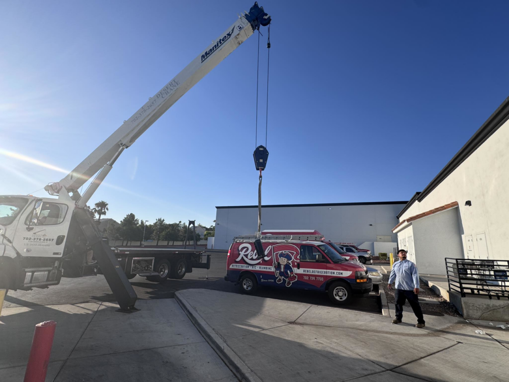 A crane truck and Rebel Refrigeration van on site for an HVAC installation in Las Vegas, NV.