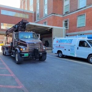 A crane truck and service van at a commercial job site for Complete Mechanical Solutions in Novi, MI.