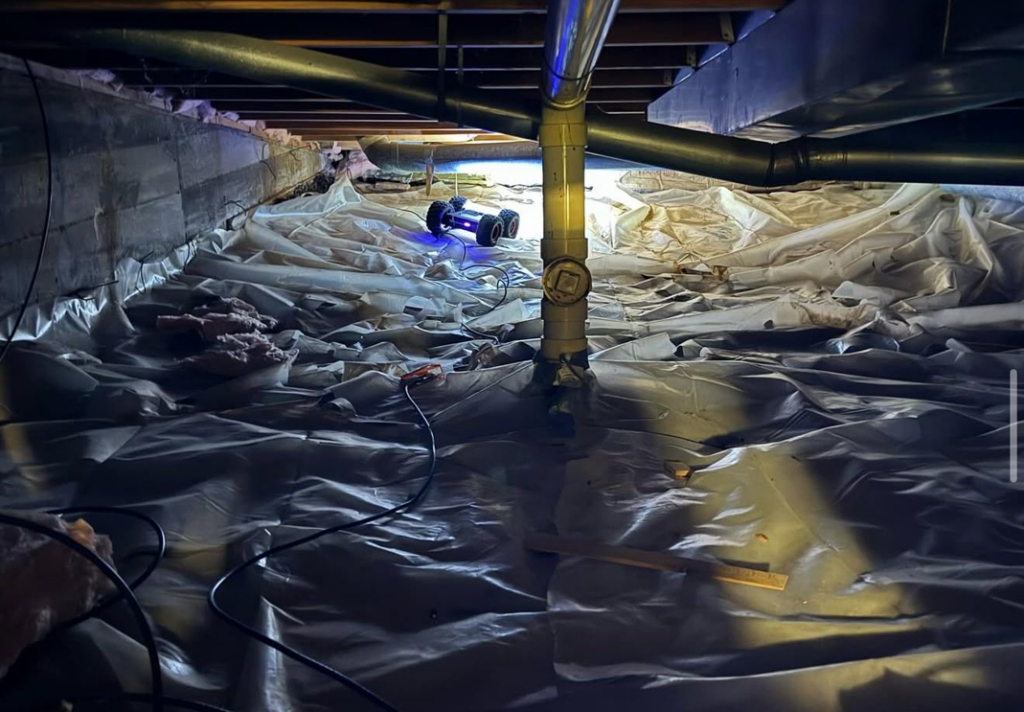 A robot with a light inspecting a crawl space with a vapor barrier, part of a pest control service by Tailor Made Pest and Wildlife in Louisville, KY.