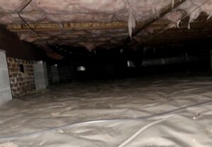 A wide view of a crawl space with a newly installed moisture barrier by Perry Crawl Space & Pest Control Solutions LLC in Chesapeake, VA.